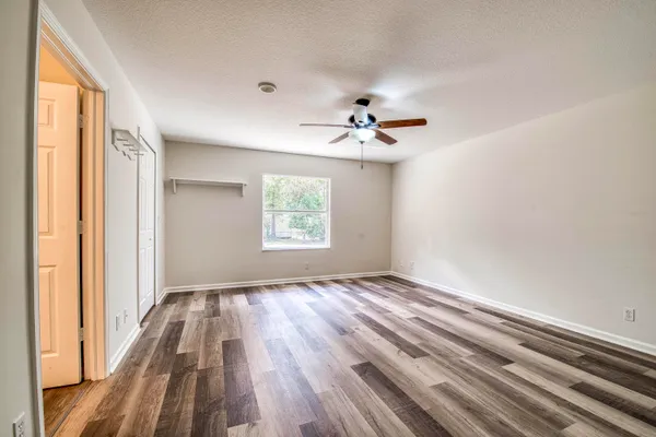 a view of empty room with wooden floor and fan