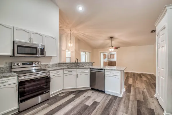 a kitchen with stainless steel appliances granite countertop a stove top oven a sink dishwasher and a refrigerator