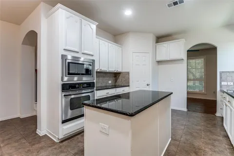 a kitchen with granite countertop a stove sink and refrigerator