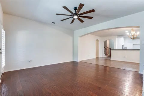 an empty room with wooden floor and a ceiling fan