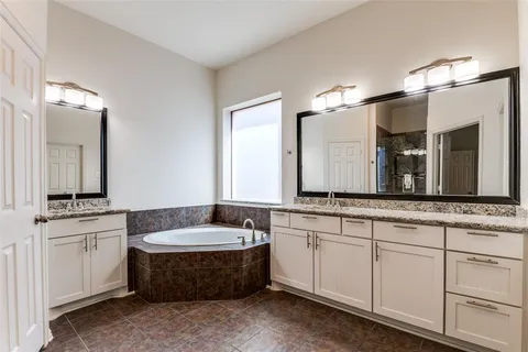 a bathroom with a double vanity sink large mirror and bathtub
