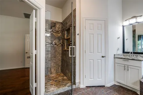 a bathroom with a granite countertop shower a mirror and a sink