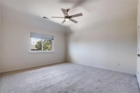 an empty room with ceiling fan and windows