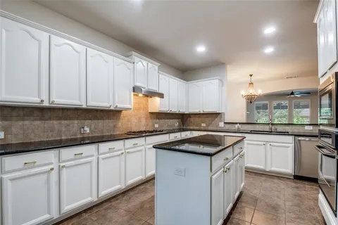 a kitchen with granite countertop sink stove and cabinets