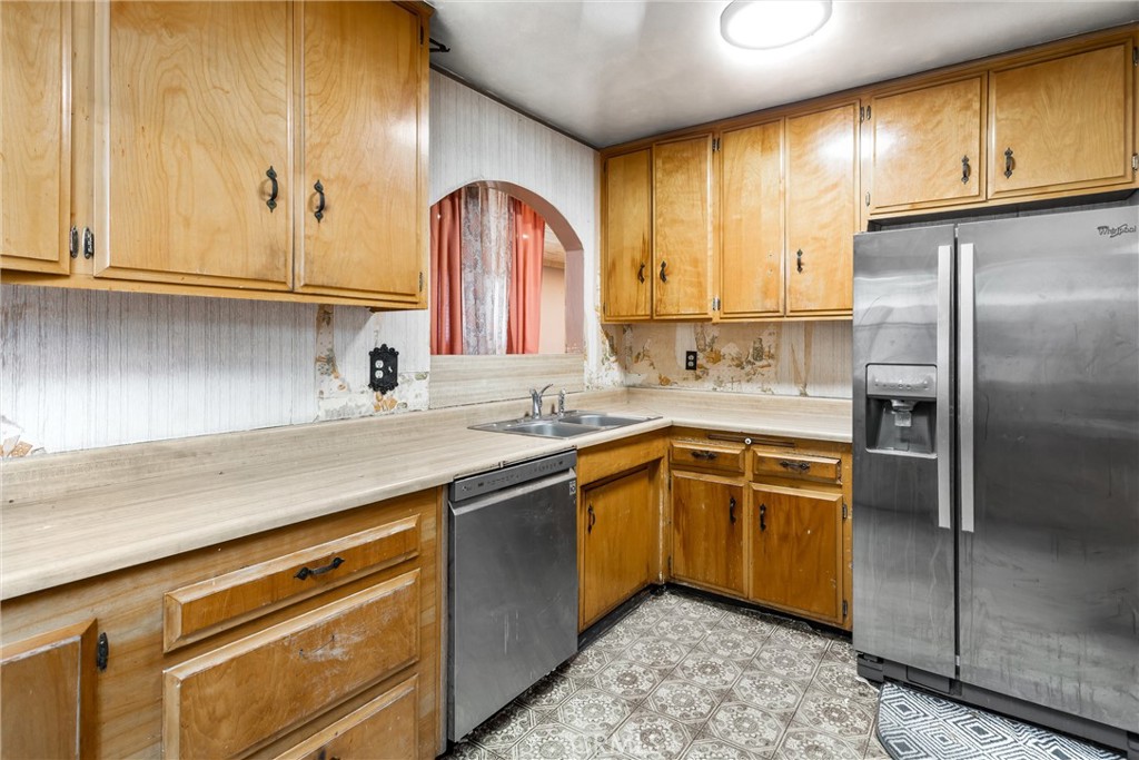 450 West Cromwell Street Rialto, CA 92376 - Photo 11 of 35 Kitchen has laminate counter tops, laminate flooring, plenty of cabinets, dishwasher (Unsure if it works) refrigerator. Window opens to bonus room