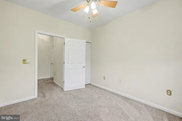 an empty room with a chandelier fan and closet area