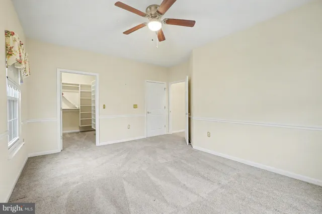 an empty room with closet and a ceiling fan