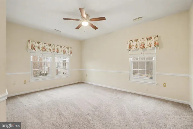 an empty room with windows and fan