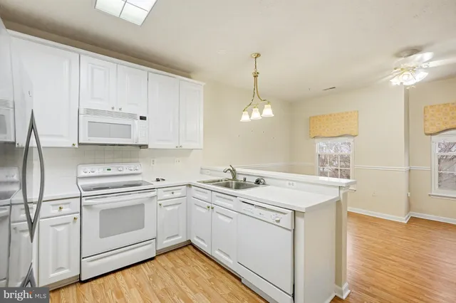 a kitchen with a sink dishwasher and white cabinets with wooden floor
