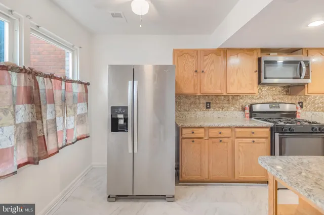 a kitchen with stainless steel appliances granite countertop a refrigerator and a stove top oven