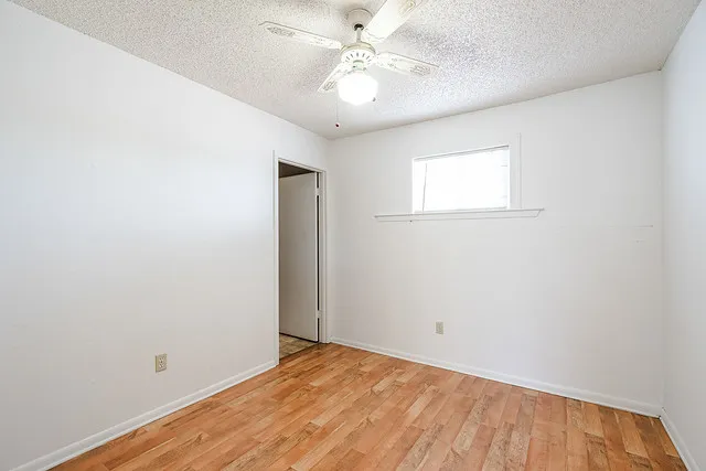 an empty room with a window and a fan