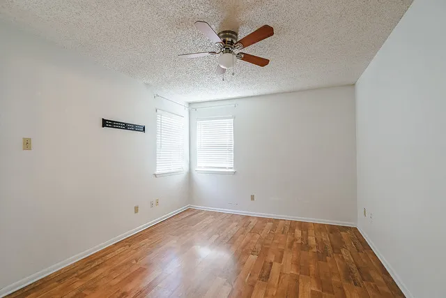an empty room with a window and ceiling fan
