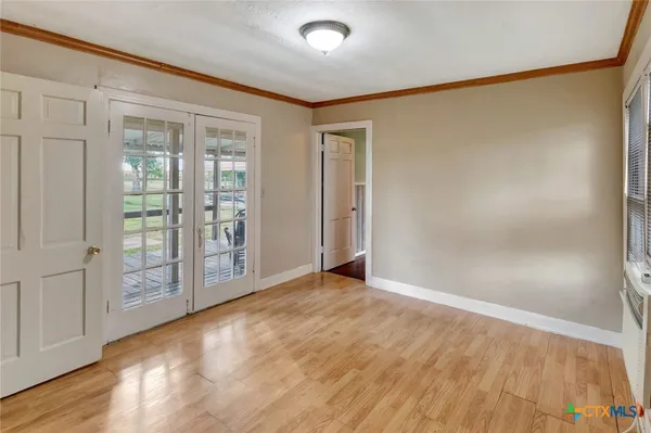 a view of an empty room with wooden floor and a window