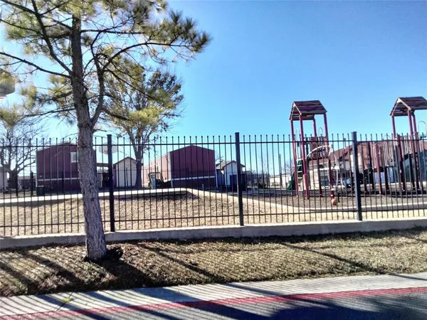a view of a yard with wooden fence and large trees