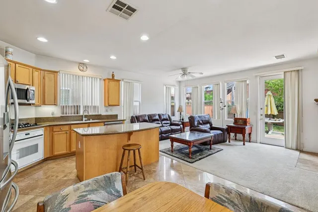 a kitchen with stainless steel appliances granite countertop a stove a sink a refrigerator white cabinets and wooden floor