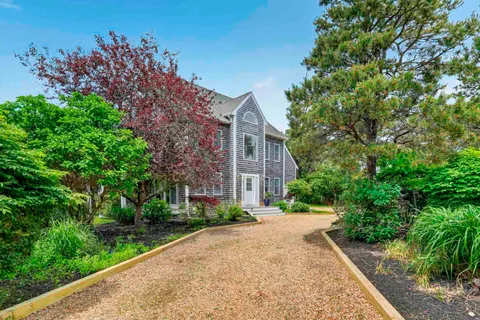 a view of a brick house with a yard and large trees
