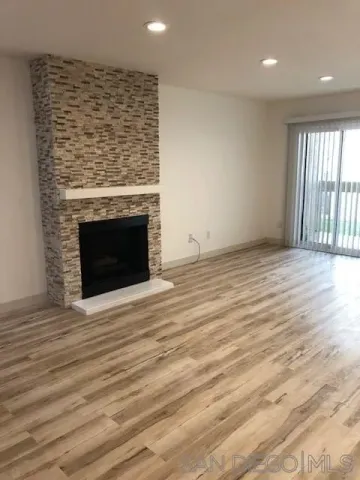an empty room with wooden floor fireplace and windows