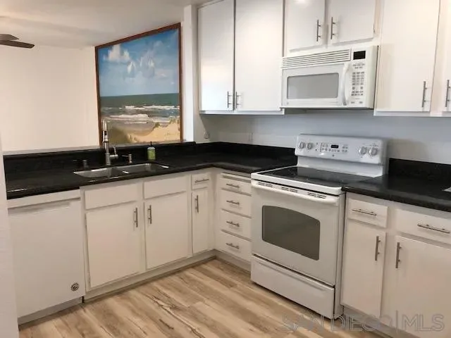 a kitchen with granite countertop white cabinets stainless steel appliances and sink
