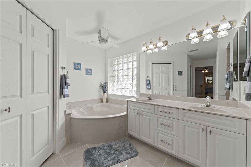 13541 Stringfellow Road Bokeelia, FL 33922 - Photo 16 of 49 a bathroom with a double vanity sink a mirror a bathtub and shower