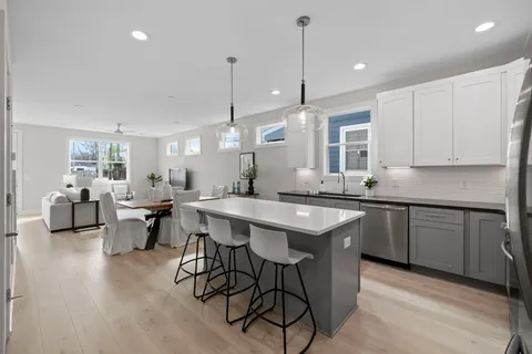 a kitchen with stainless steel appliances a sink a stove a refrigerator and white cabinets with wooden floor