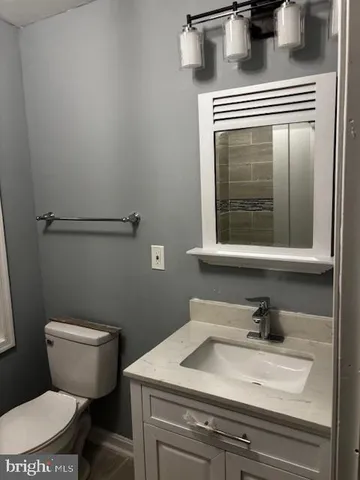 a bathroom with a granite countertop sink a toilet and a mirror