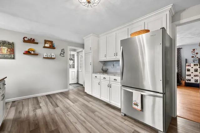 a kitchen with stainless steel appliances a refrigerator a stove a sink and white cabinets with wooden floor