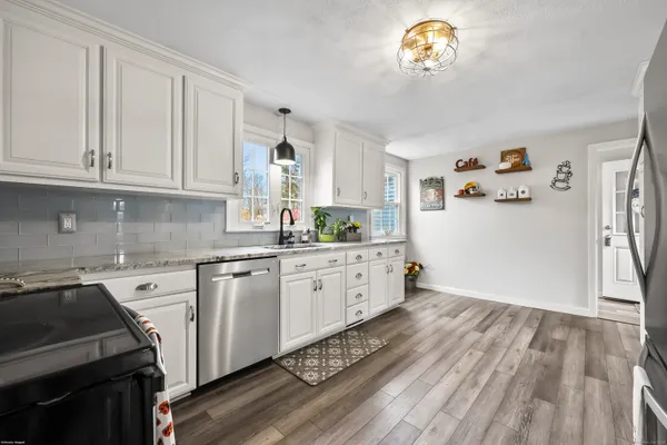 a kitchen with granite countertop a white stove top oven and white cabinets