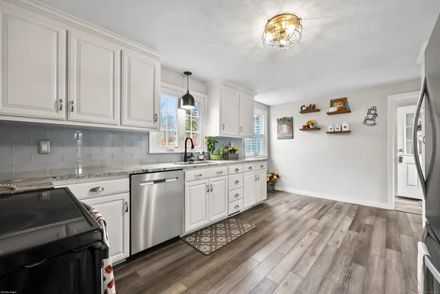 a kitchen with granite countertop a white stove top oven and white cabinets