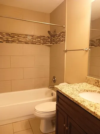 a bathroom with a granite countertop bathtub sink vanity and toilet