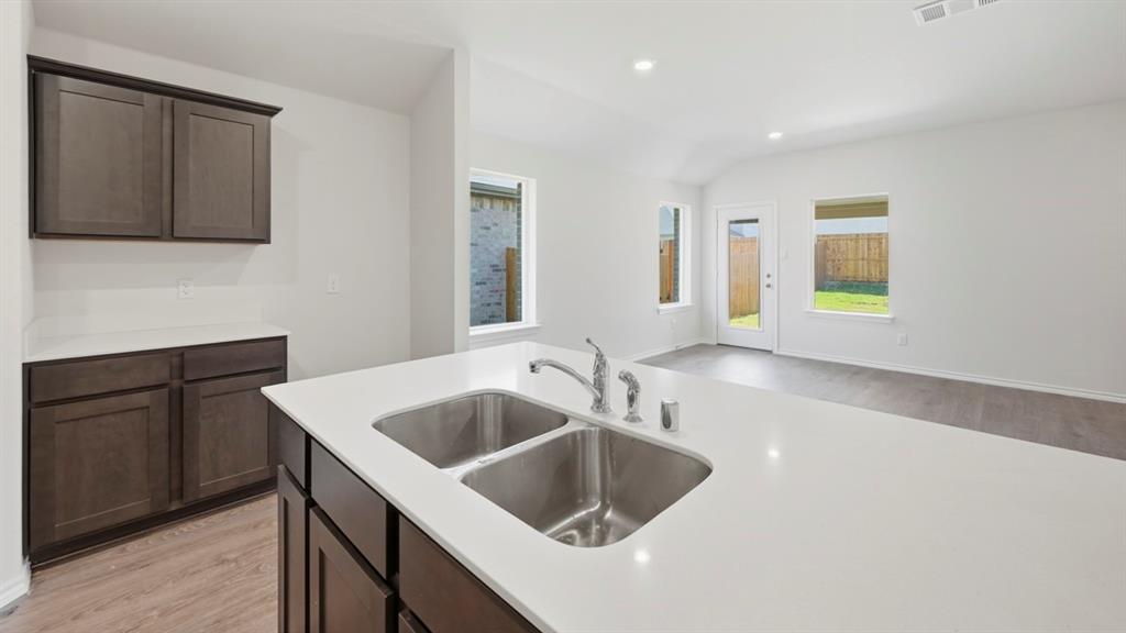 312 Wild Rose Way Princeton, TX 75407 - Photo 24 of 39 a kitchen with a sink and a stove top oven with wooden floor