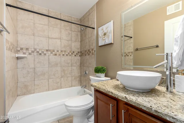 a bath room with a granite countertop toilet a sink and a bathtub