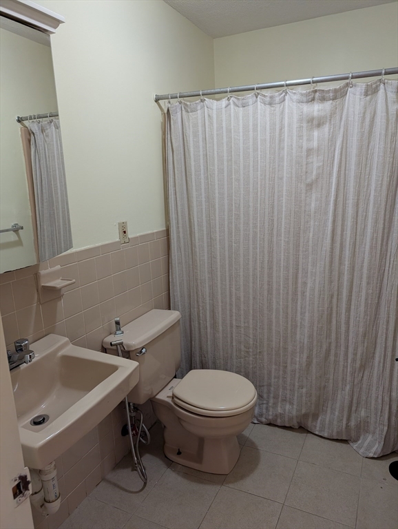 569 Somerville Avenue, Unit 5 Somerville, MA 02143 - Photo 6 of 8 a bathroom with a sink a toilet and shower curtain