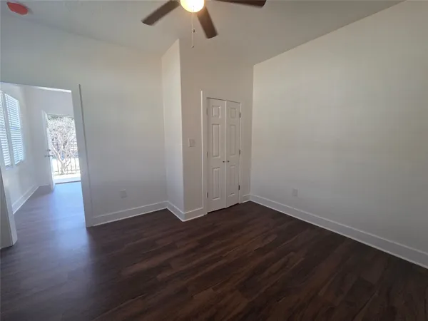 an empty room with wooden floor chandelier fan and windows