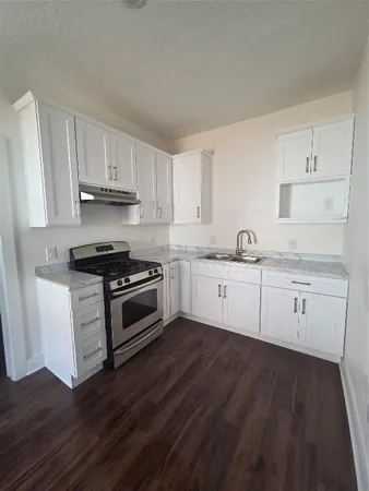 a kitchen with granite countertop a sink cabinets and stainless steel appliances