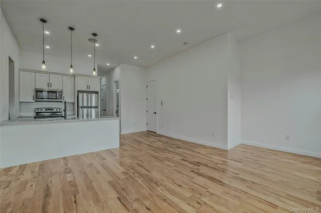 a view of kitchen with kitchen island wooden floor center island and stainless steel appliances