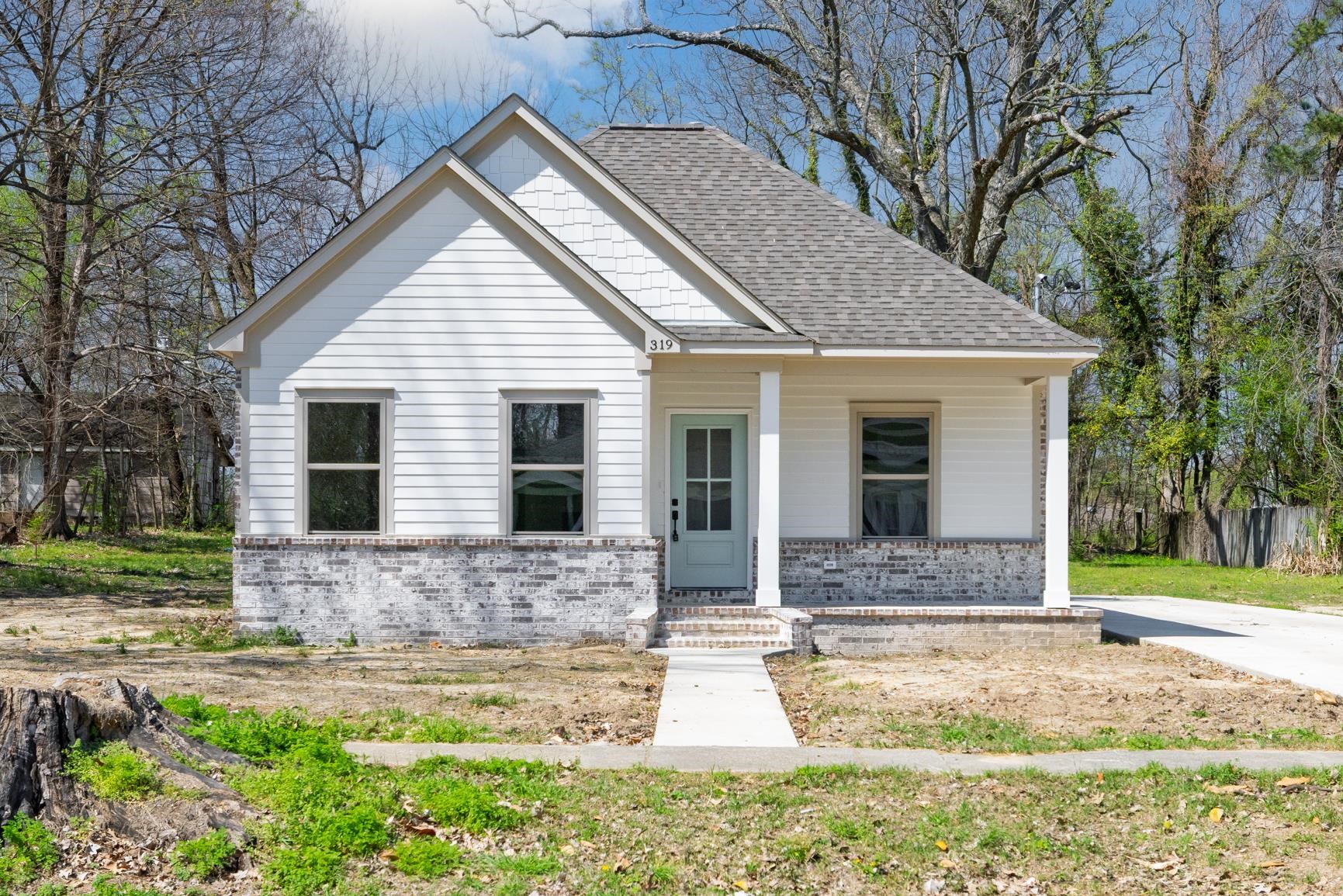 Bungalow-style home with covered porch, brick siding, and roof with shingles