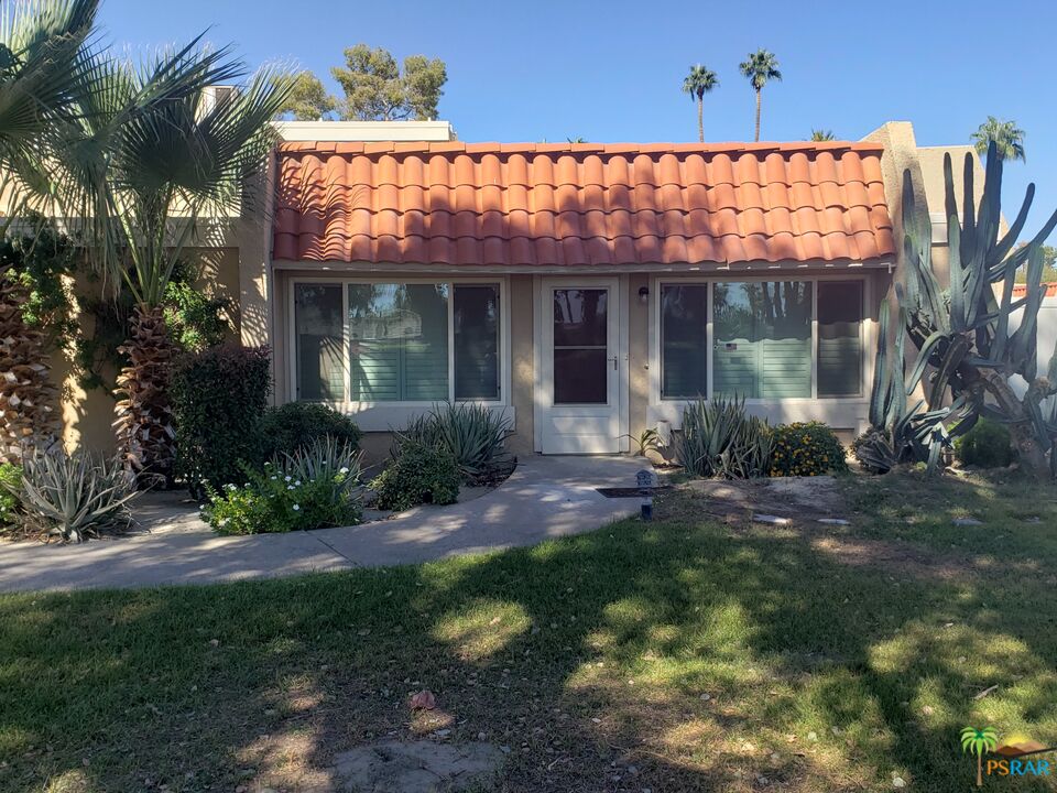 a view of a house with a small yard and potted plants