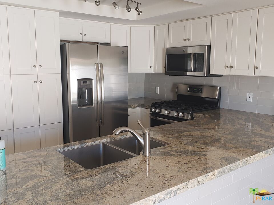 35989 Alameda Court Rancho Mirage, CA 92270 - Photo 3 of 4 a kitchen with stainless steel appliances granite countertop a sink a microwave a refrigerator and a counter space