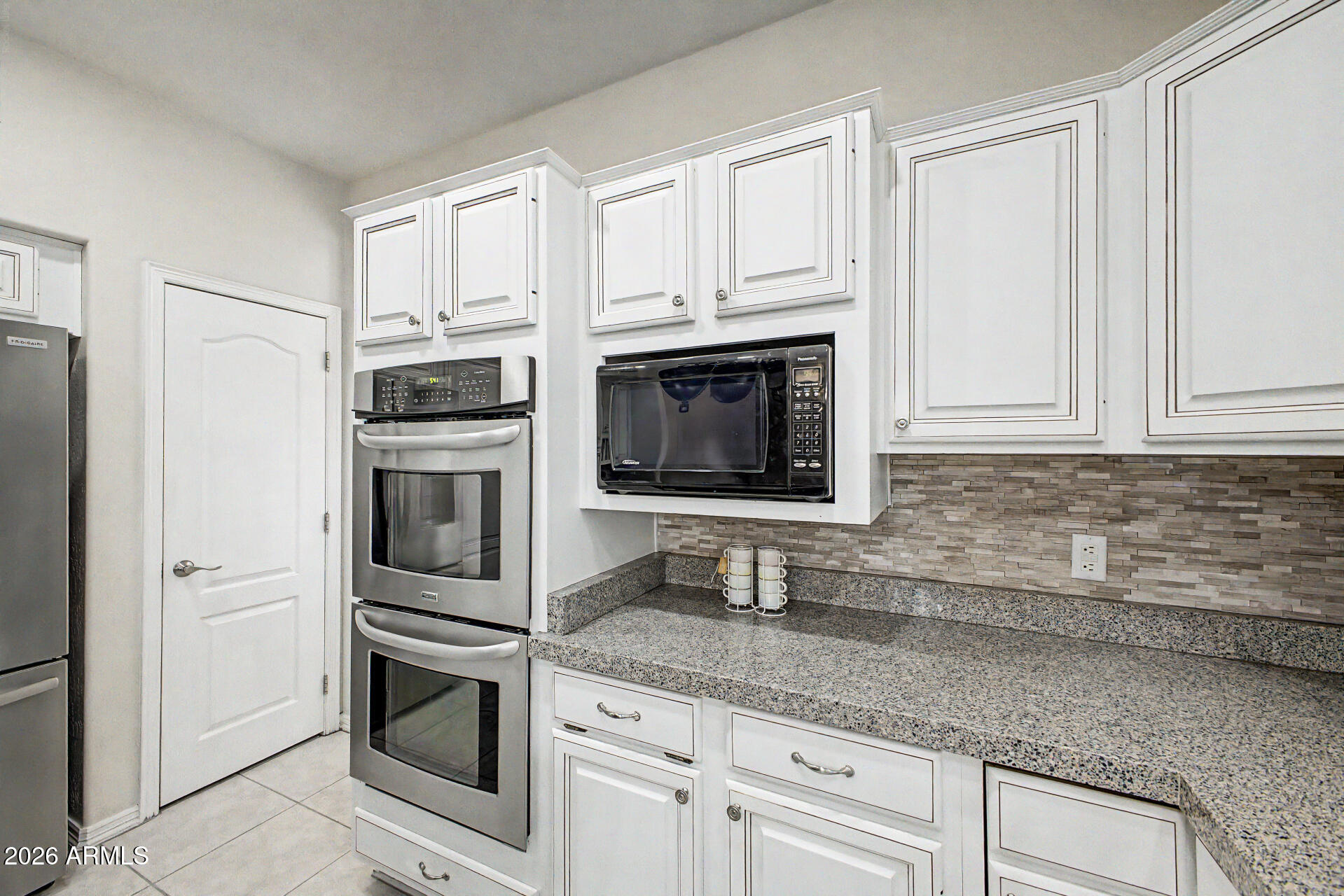 1124 North Robin Lane Mesa, AZ 85213 - Photo 59 of 87 a kitchen with granite countertop white cabinets stainless steel appliances and sink