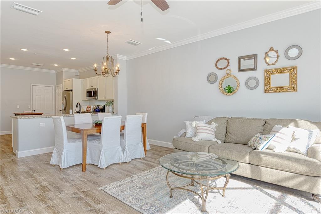 a living room with couches and kitchen view with wooden floor