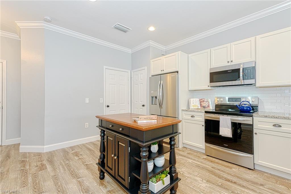 988 Hampton Circle Naples, FL 34105 - Photo 7 of 20 a kitchen with stainless steel appliances granite countertop a stove top oven a sink and a refrigerator