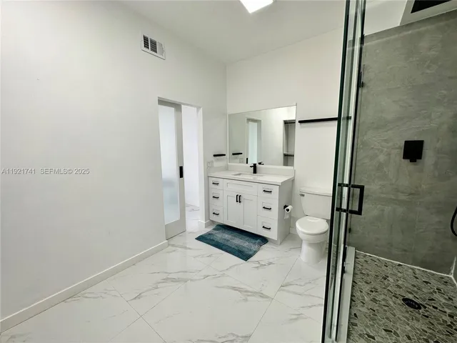 a spacious bathroom with a double vanity sink a toilet and a shower