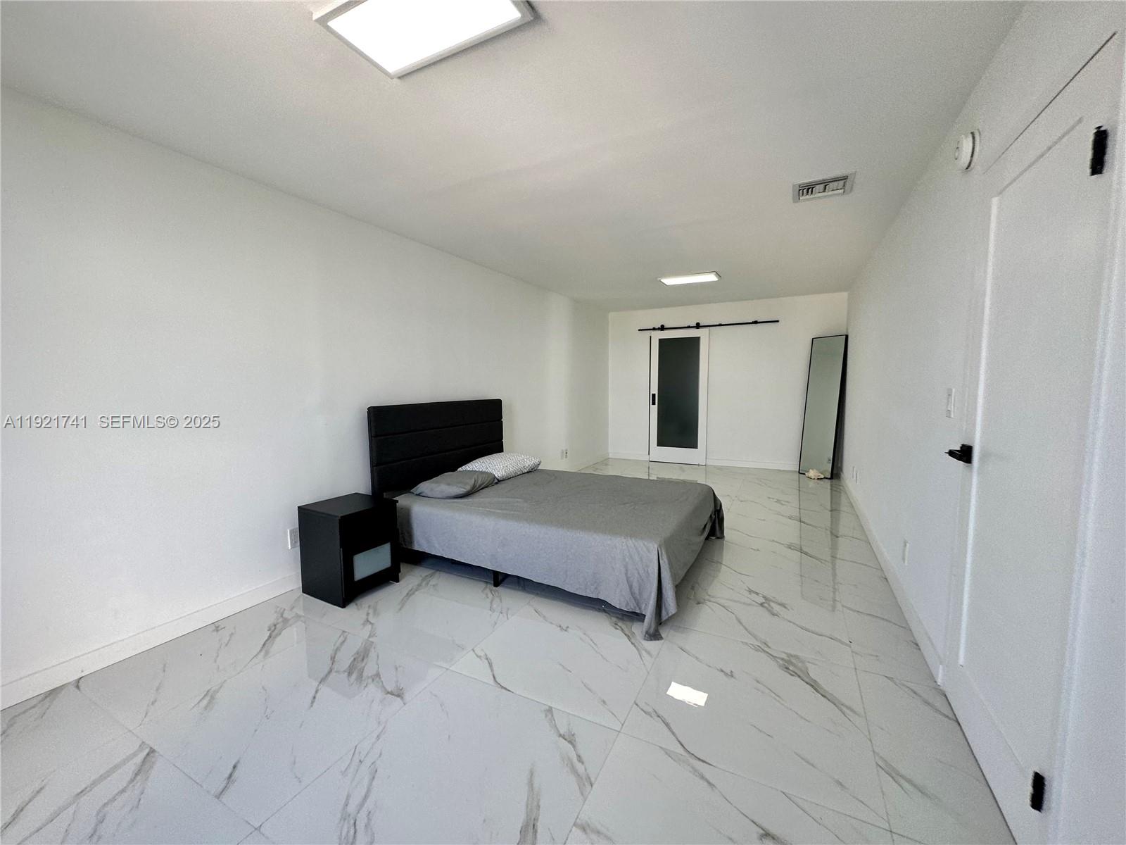 13499 Biscayne Boulevard, Unit PH1709 North Miami, FL 33181 - Photo 7 of 11 a spacious bedroom with a bed and wooden floor