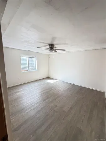 an empty room with wooden floor cabinet and windows