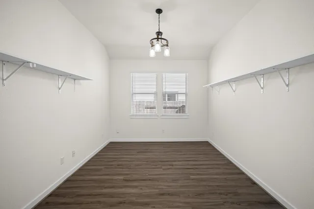 a view of an empty room with wooden floor and windows