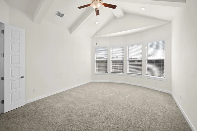 an empty room with chandelier fan and windows
