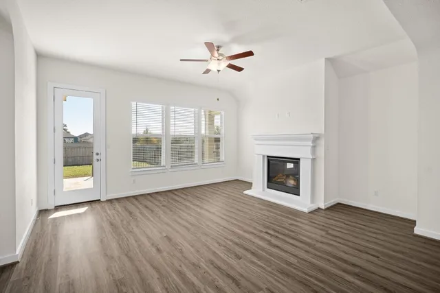 a view of an empty room with wooden floor fireplace and a window