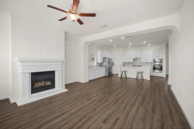 a view of a kitchen and an empty room with wooden floor
