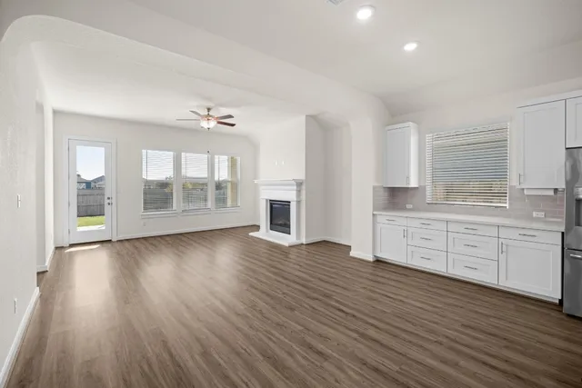 wooden floor in an empty room with a kitchen and a window