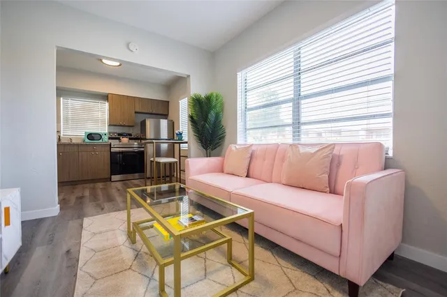a living room with furniture a large window and kitchen view